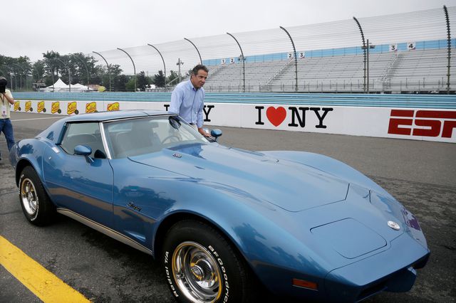 Governor Cuomo, in a button down shirt and khakis, gets ready to climb into a powder blue classic Corvette